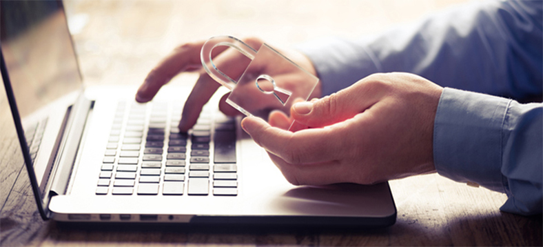 Male arms using one hand to type on a laptop and the other to hold a clear lock.