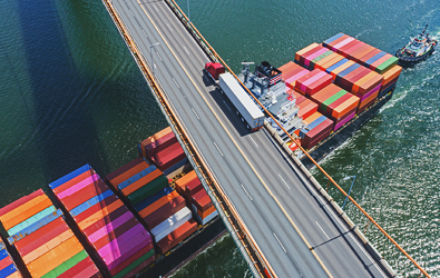 flatbed truck with shipping container along a bridge and above a shipping container ferry