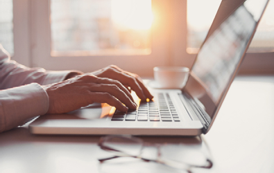 person at a table typing on a laptop