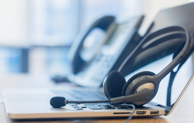 headset with microphone on a laptop beside a phone system