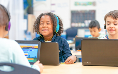 kids with headphones on in front of laptop computers