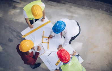 four people wearing construction helmets around a table with measurement tools