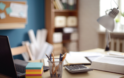 desk with post it notes, laptop, pencils and pens in a holder, lamp, notepad