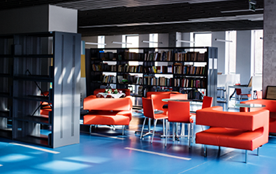 orange tables and seating among bookshelves