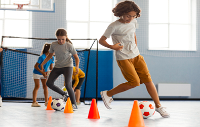 girls maneuvering around pylons with soccer balls